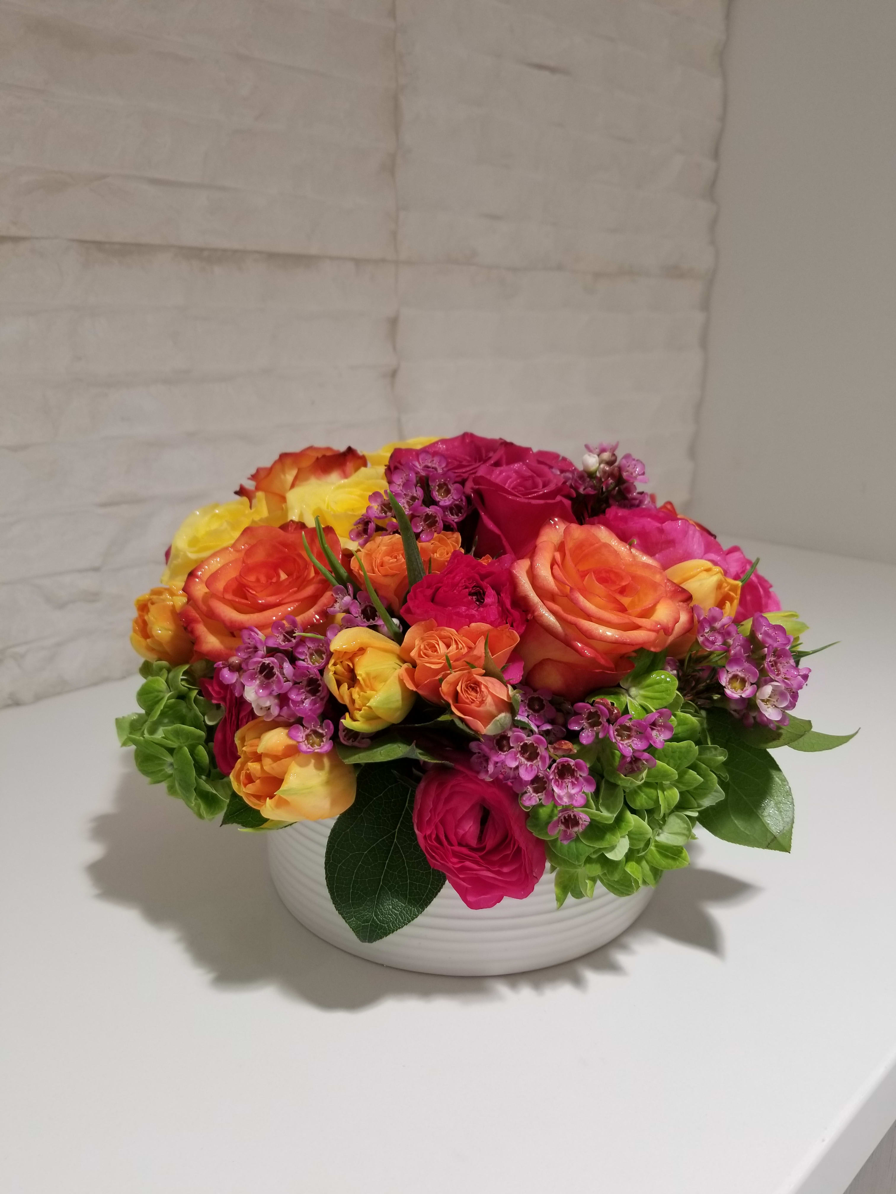 Colorful rose arrangement in a white bowl vase