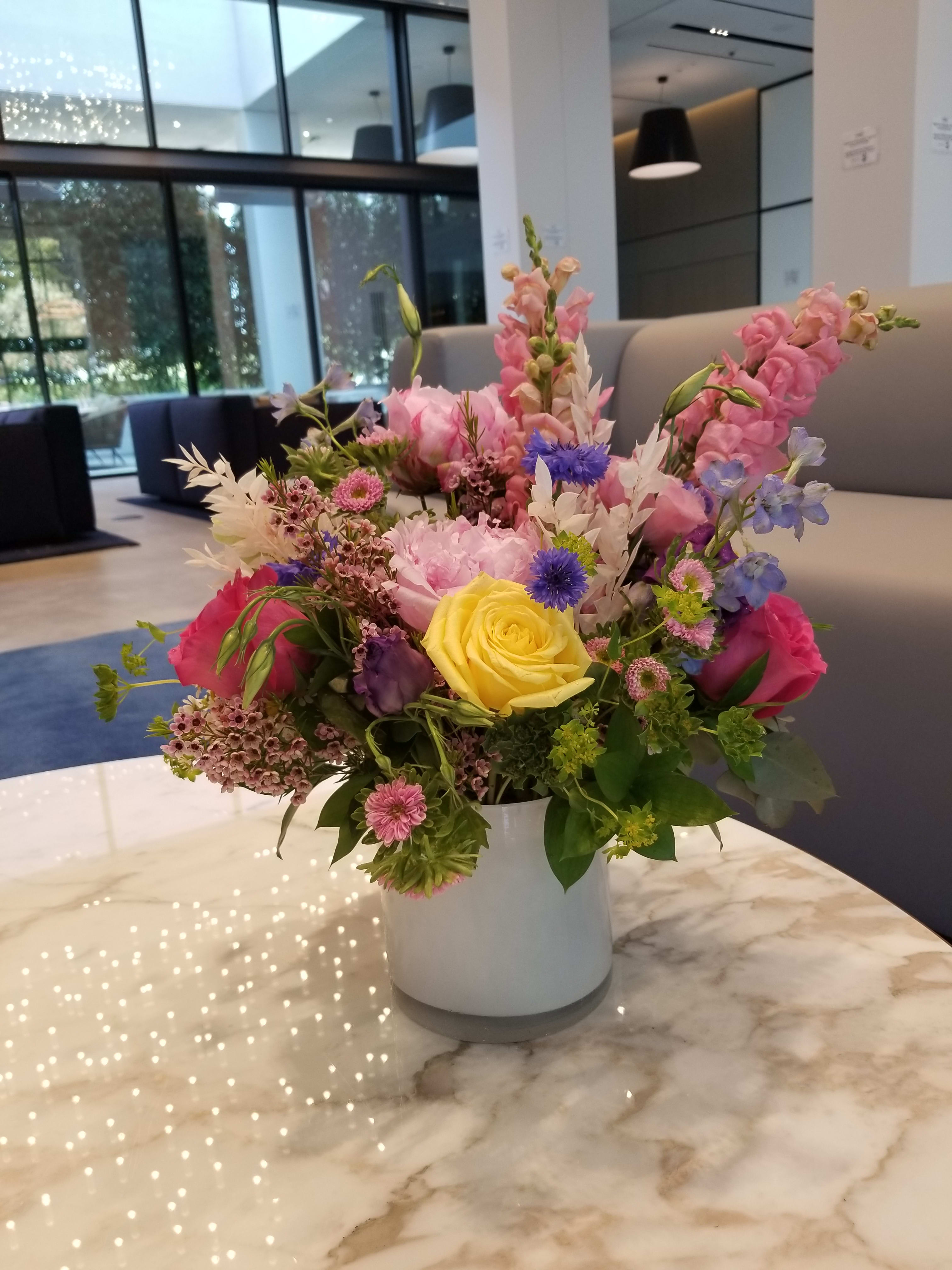 Mixed bouquet in a white vase with pink, yellow, and blue flowers