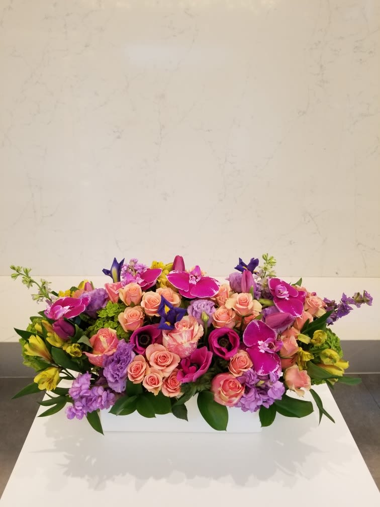 Ruth - Elongated arrangement pave style with assorted flowers and a touch of orchids.  