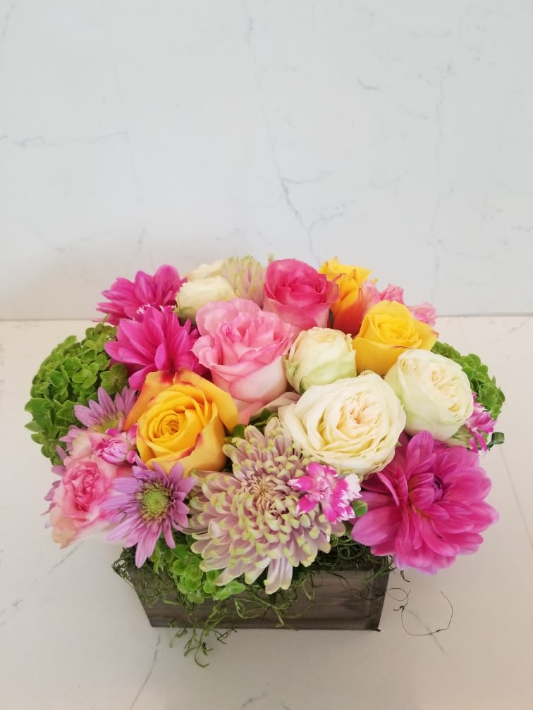 Mixed pink, yellow, and white flowers arranged in a rectangular wooden box