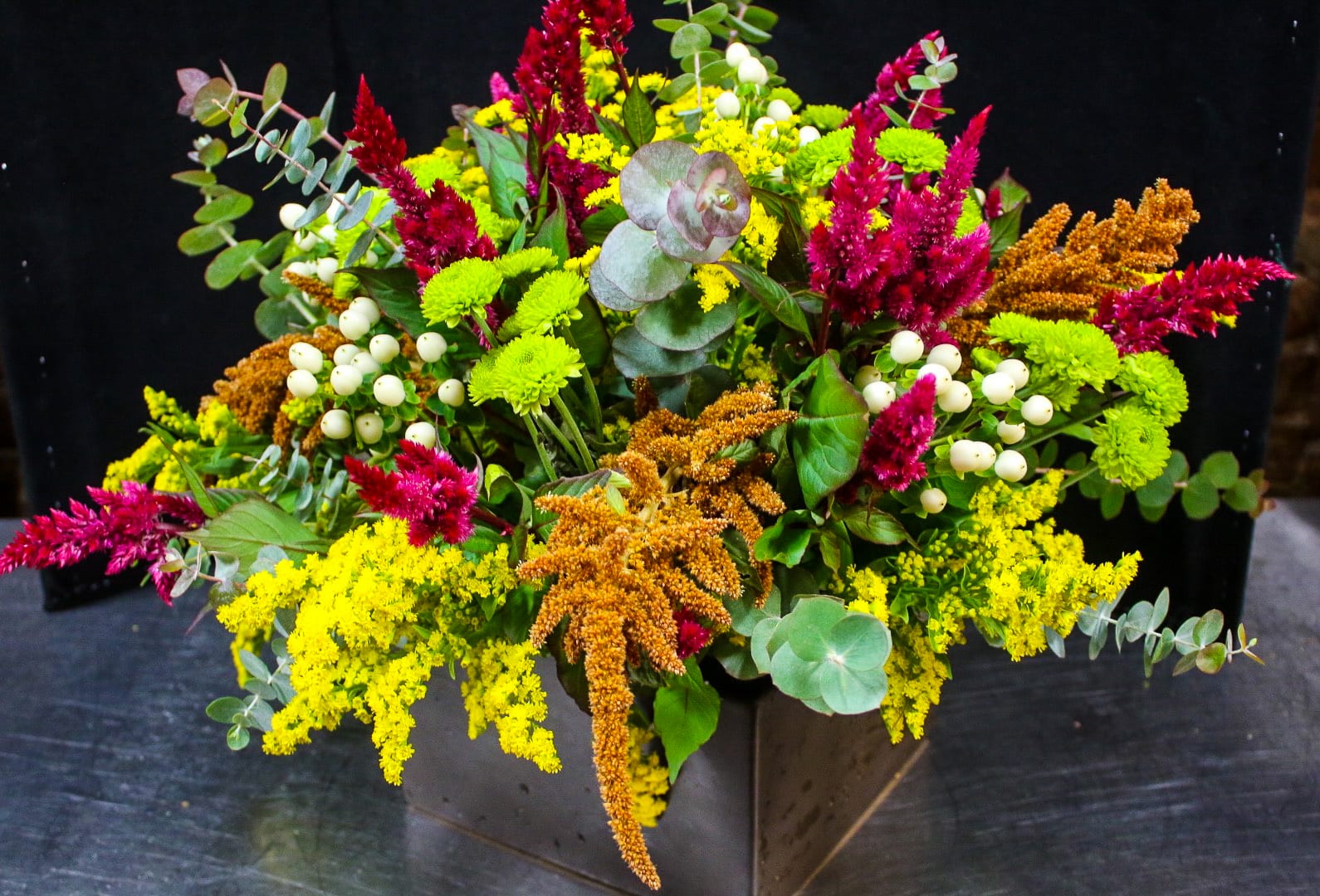 Colorful mixed flower arrangement in a dark square vase