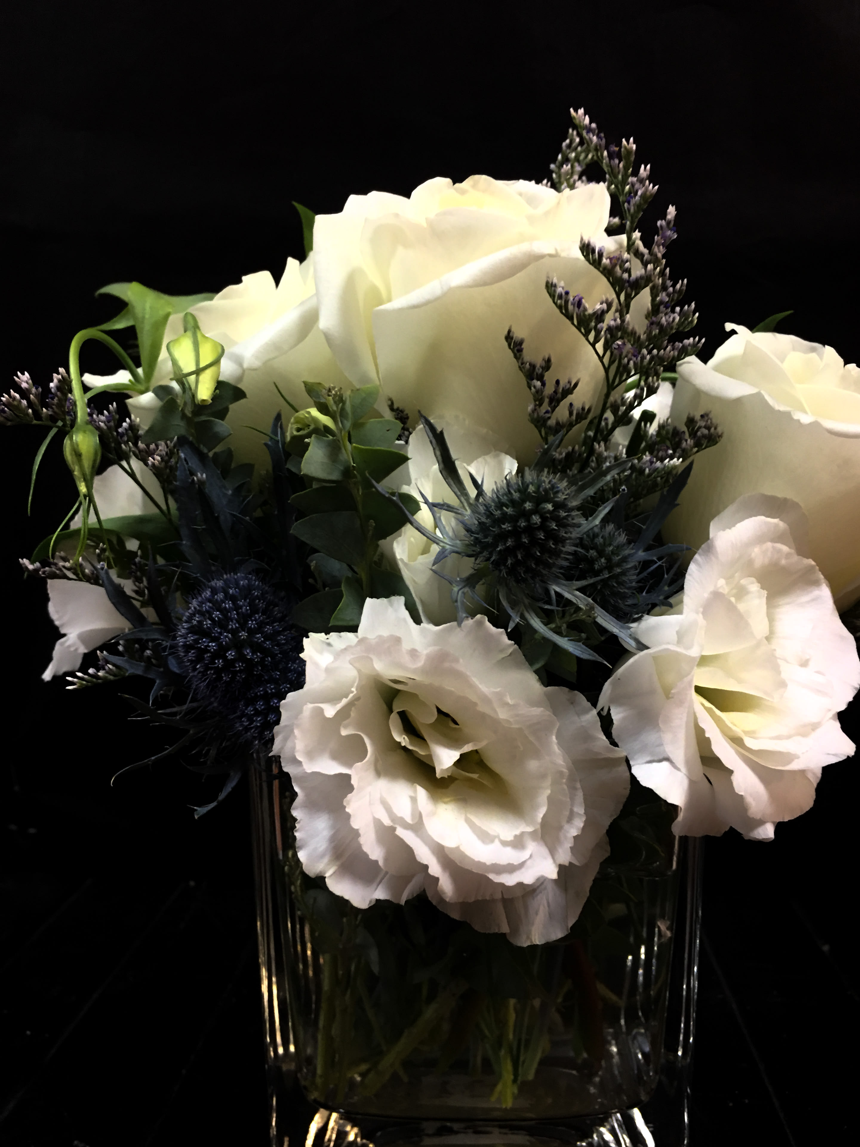 White roses and pale blooms in a clear glass vase