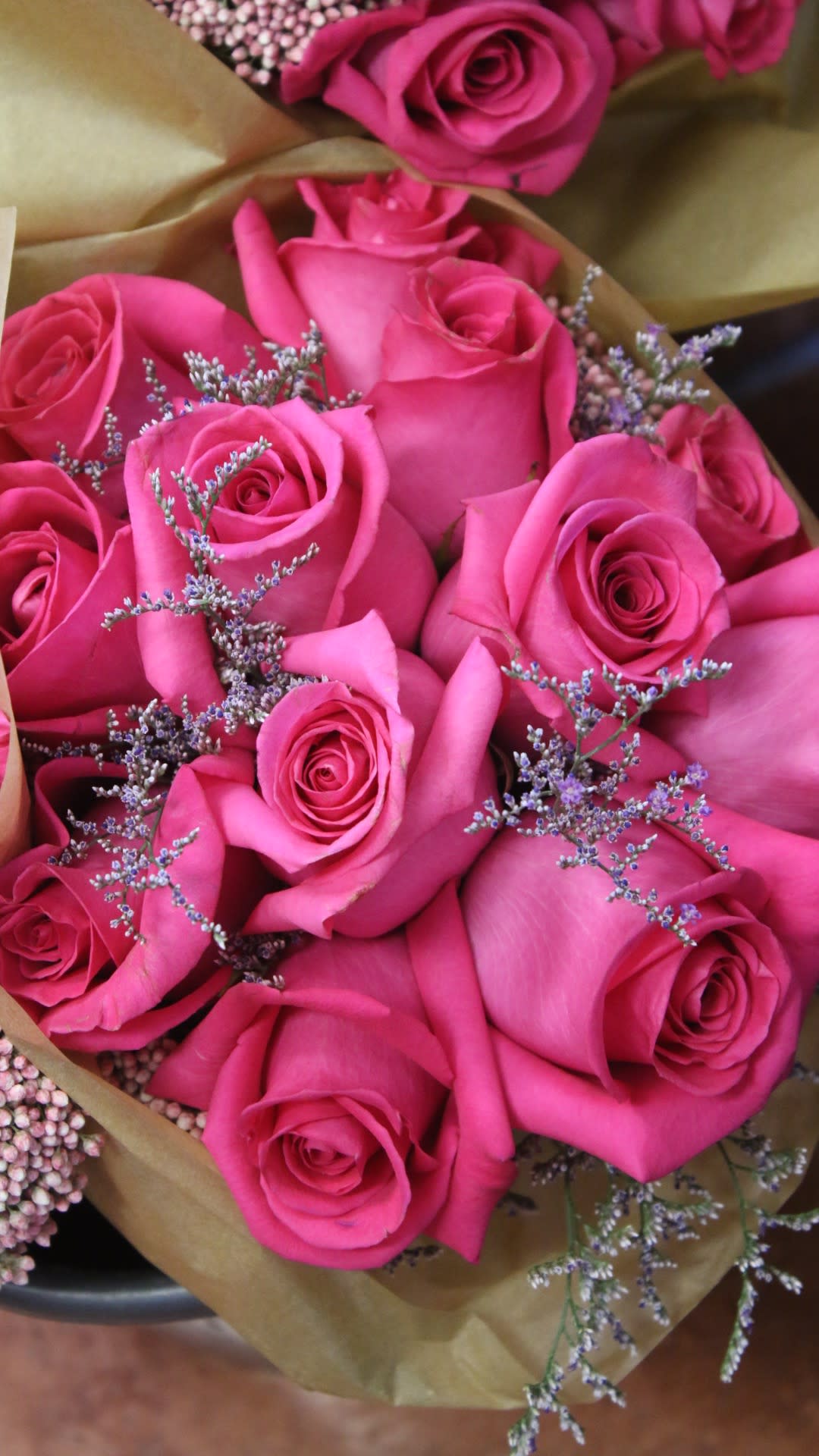 Bouquet of bright pink roses with small purple filler flowers