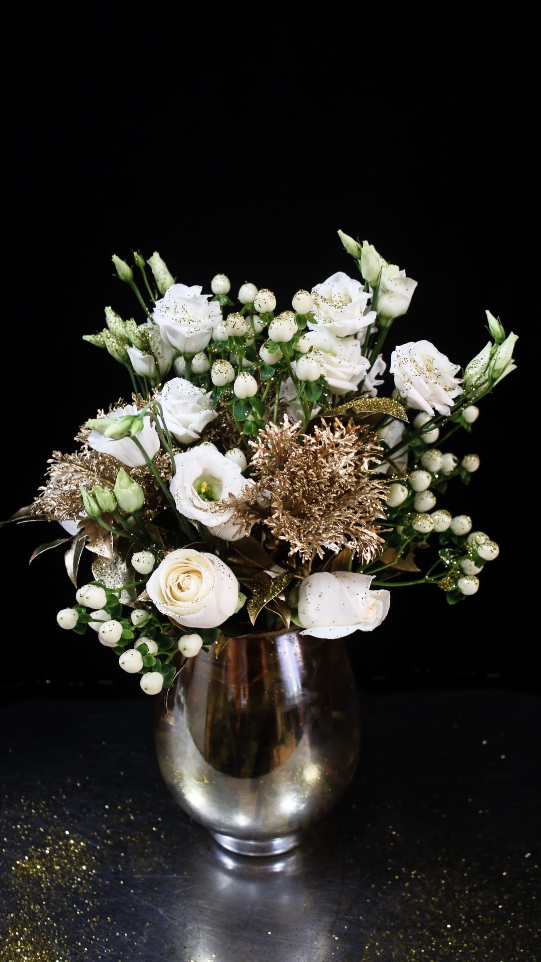 White roses and berry sprigs arranged in a glass vase