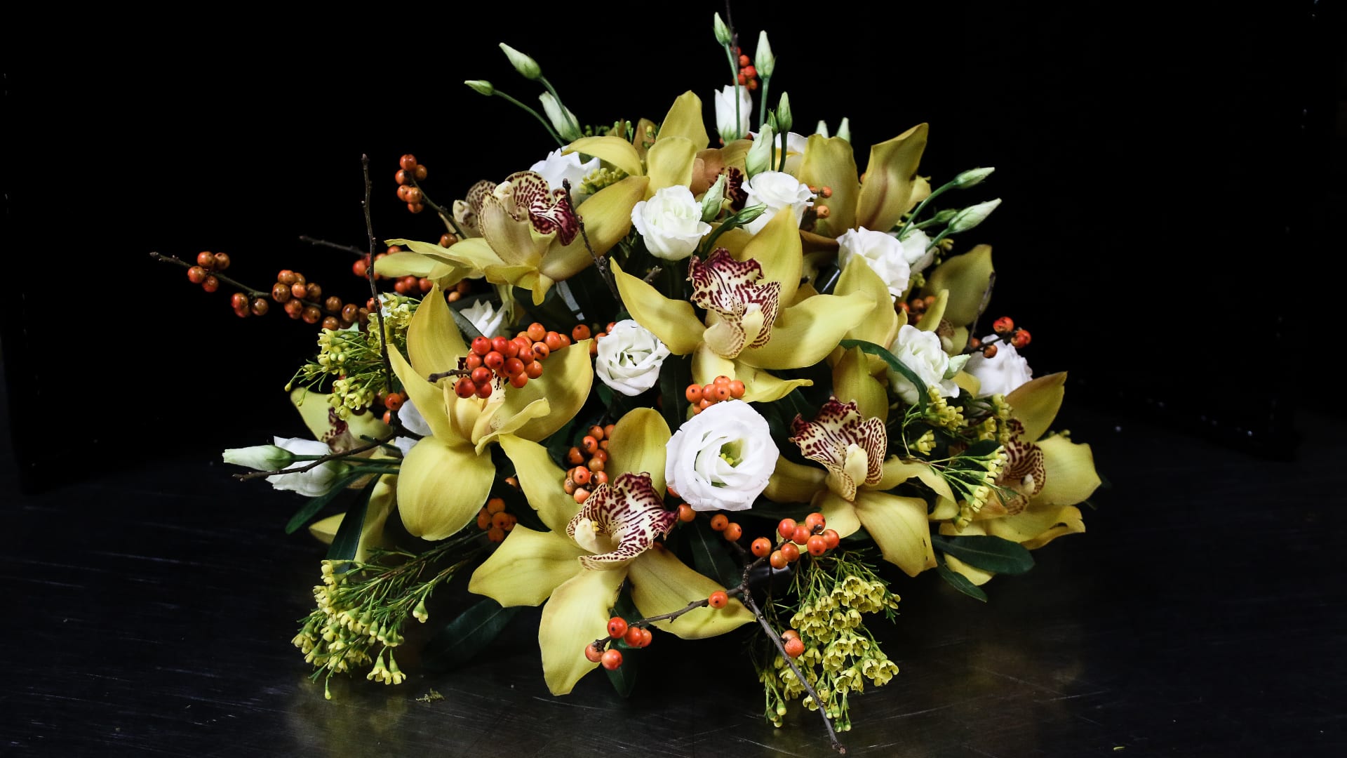 Yellow orchids and white blooms arranged with orange berries