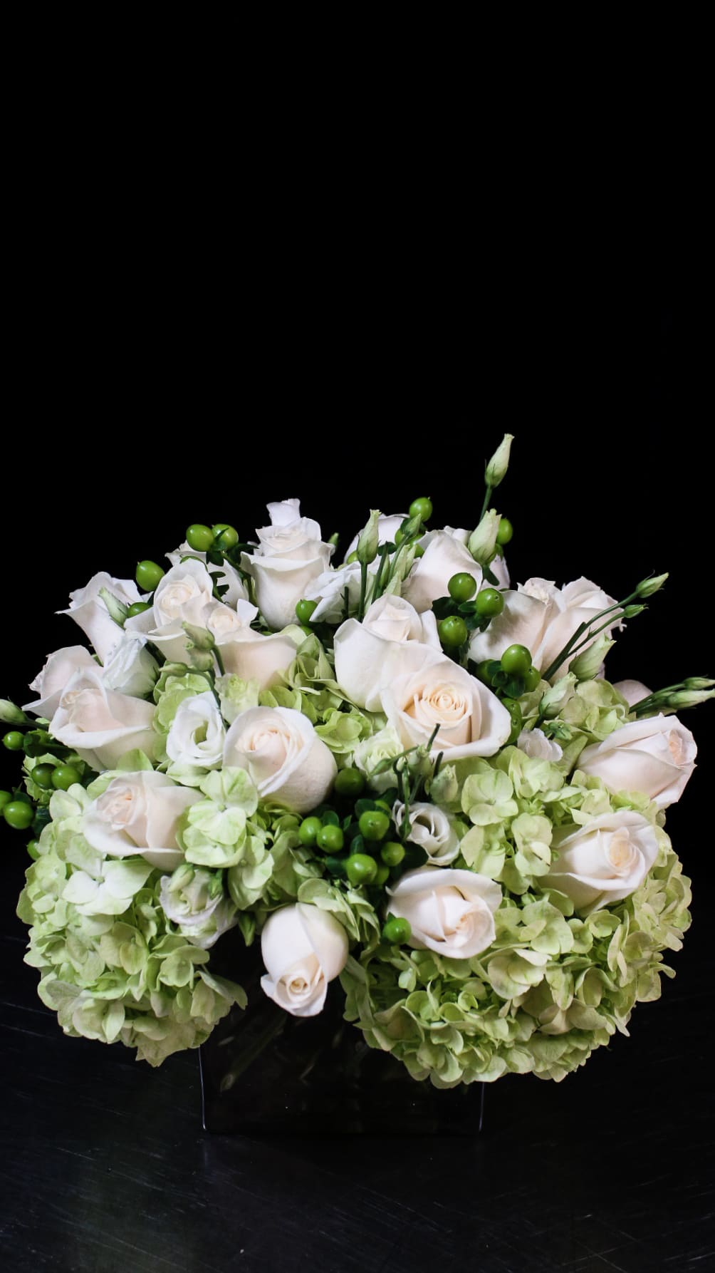 White roses and pale green hydrangeas arranged in a low bouquet