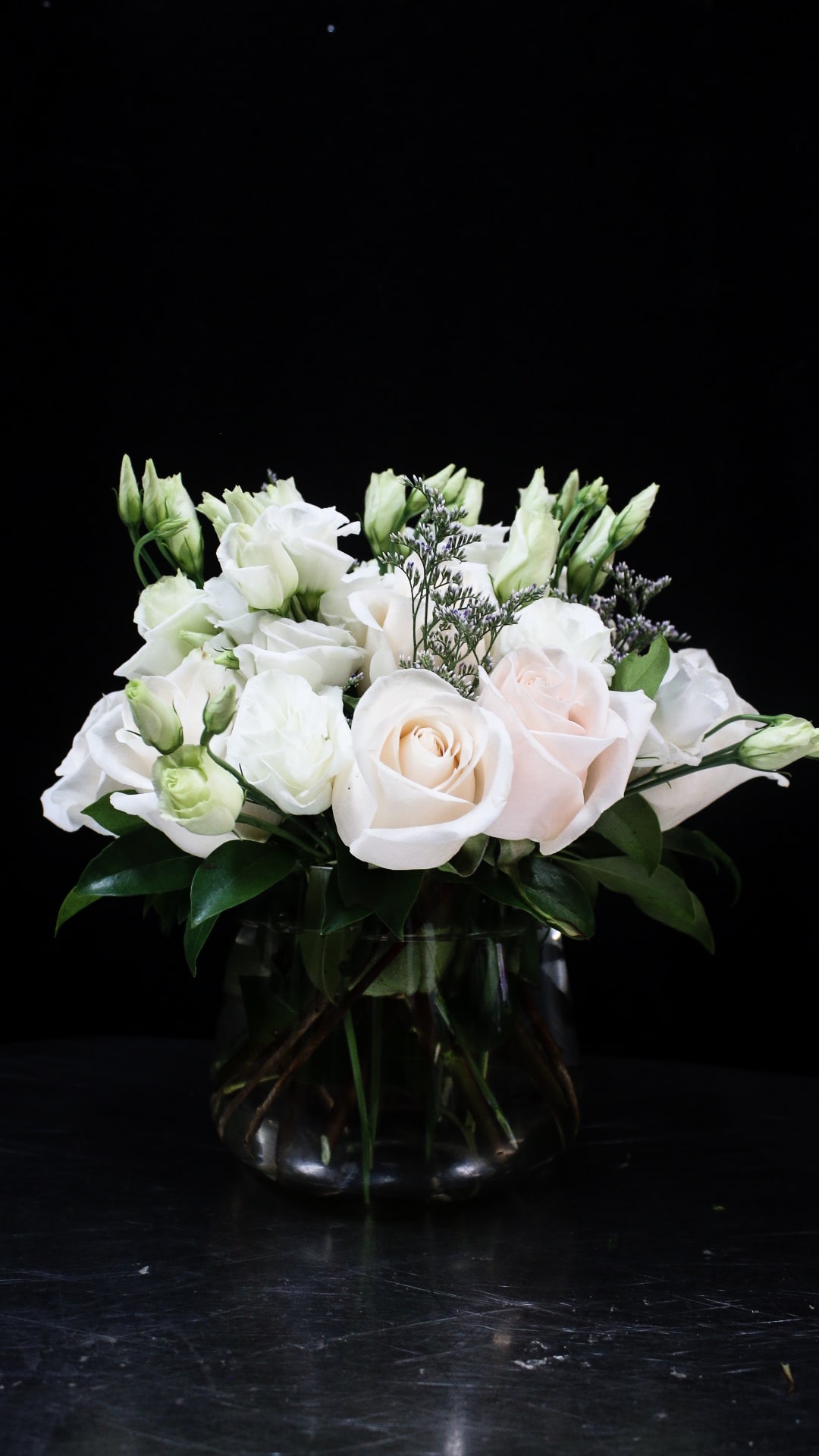 White roses and lisianthus arranged in a glass vase