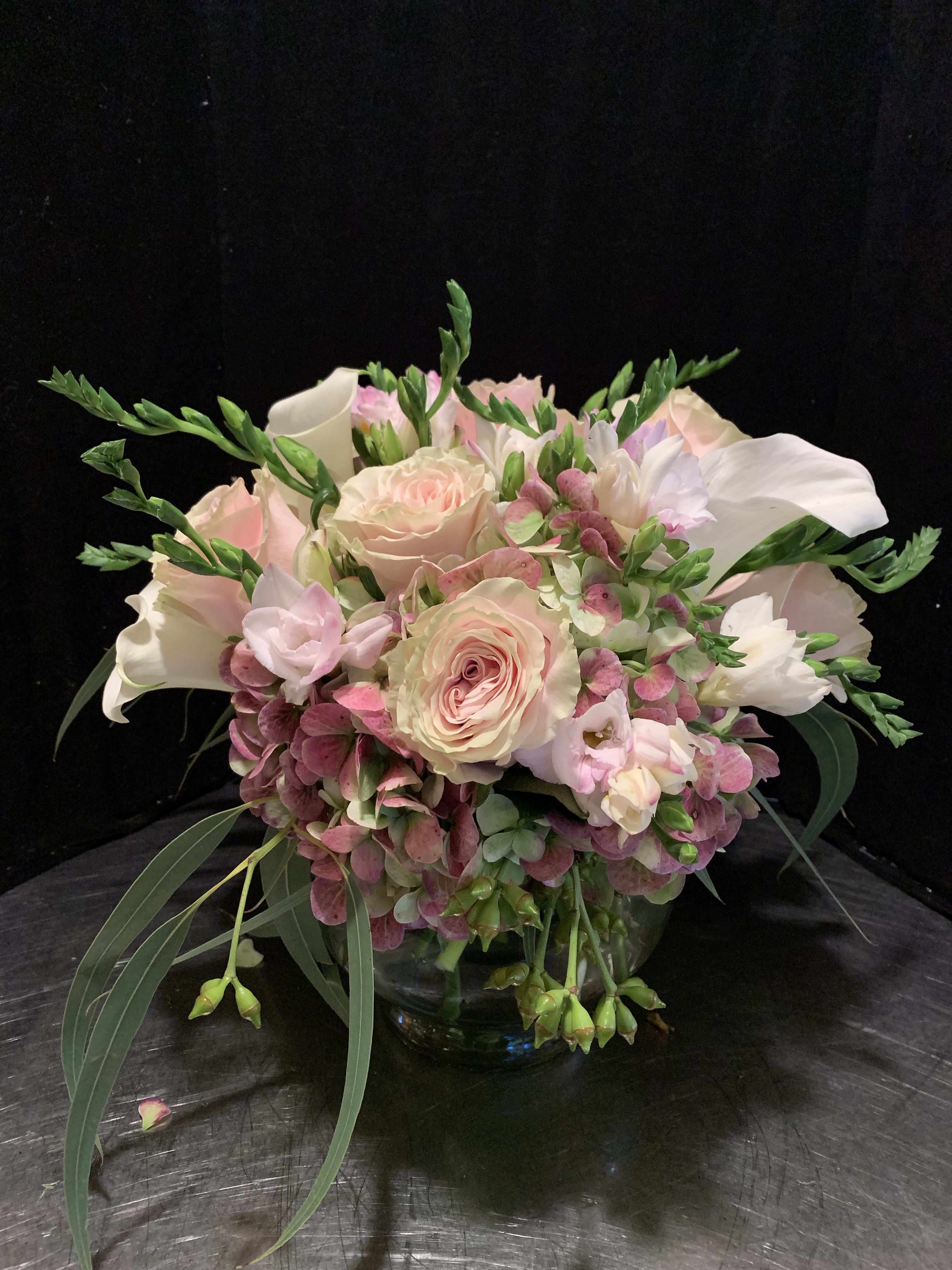 Blush roses and white calla lilies in a glass bowl vase