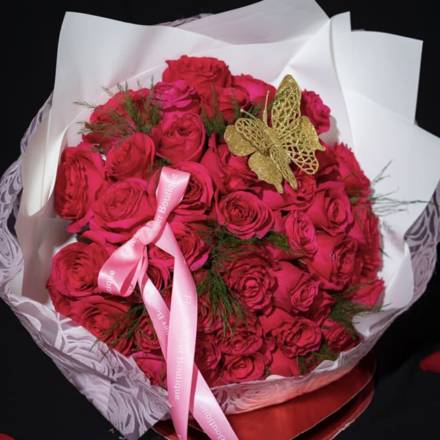 Bouquet of bright pink roses wrapped in white paper with a pink ribbon