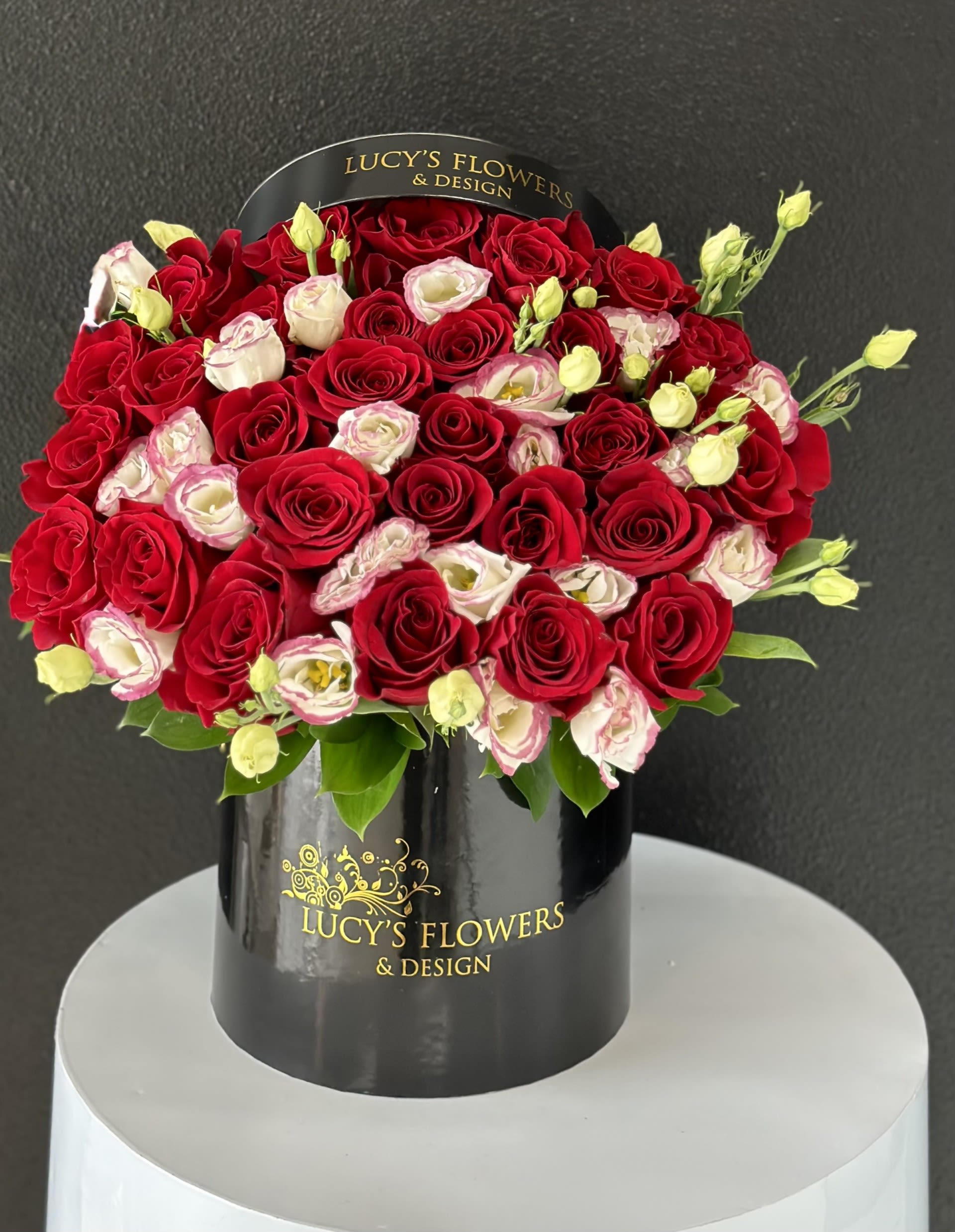 Red and white roses arranged in a black hatbox