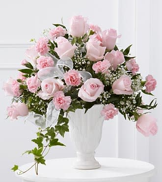Pink roses and carnations arranged in a white vase