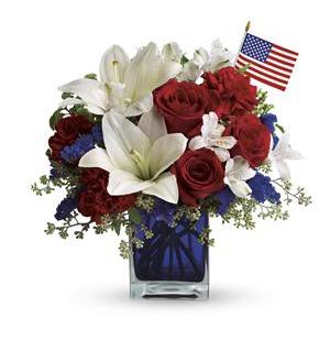 America The beautiful Bqt - A patriotic pick to send a brave veteran, decorate your Fourth of July picnic, or celebrate Memorial Day. Lush red, white and blue flowers are presented in a deep blue glass cube vase along with an American flag. Red roses, white asiatic lilies, white alstroemeria, blue statice and red carnations are gathered with green pitta negra, seeded eucalyptus and a small American flag in a cobalt blue glass cube.