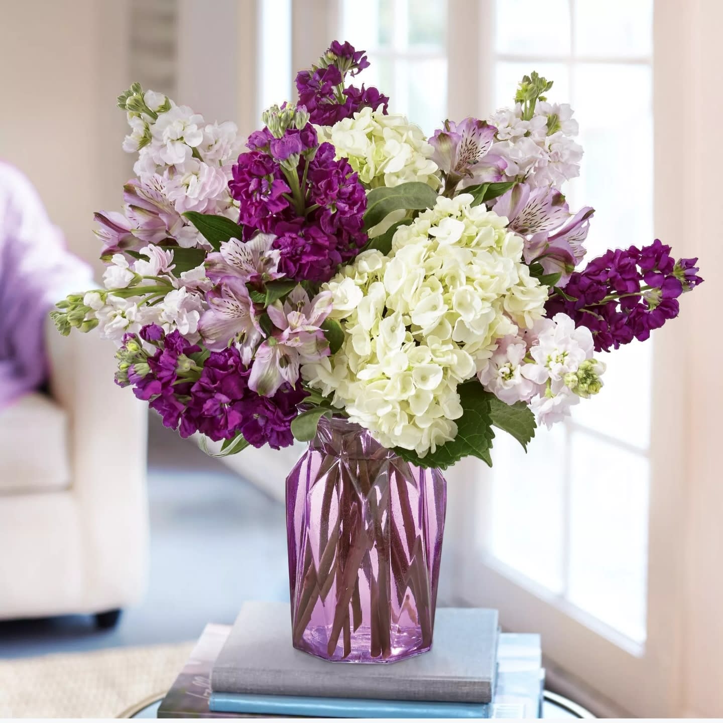 Purple and white flowers arranged in a purple glass vase