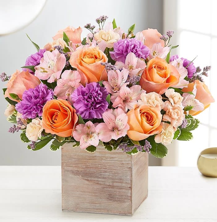 Peach and purple flower arrangement in a wooden box