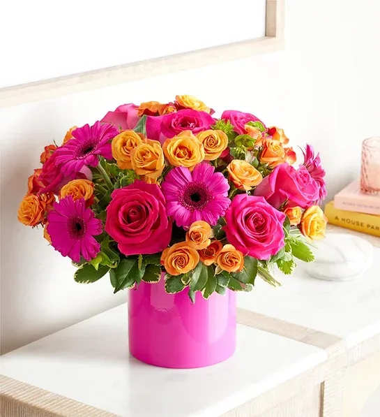 Pink and orange mixed flower arrangement in a bright pink vase