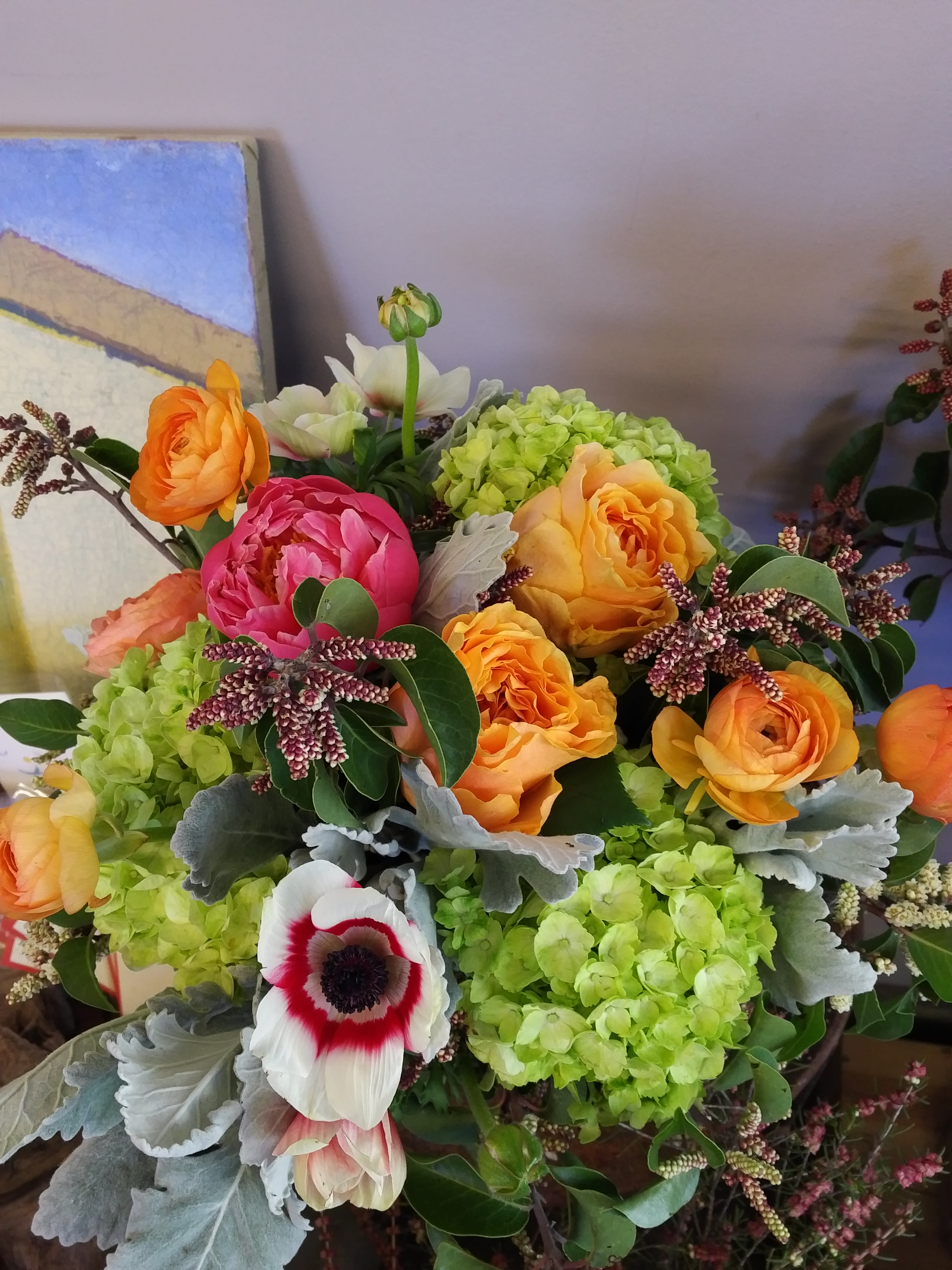 Bouquet of orange and pink flowers with green hydrangeas and a white anemone