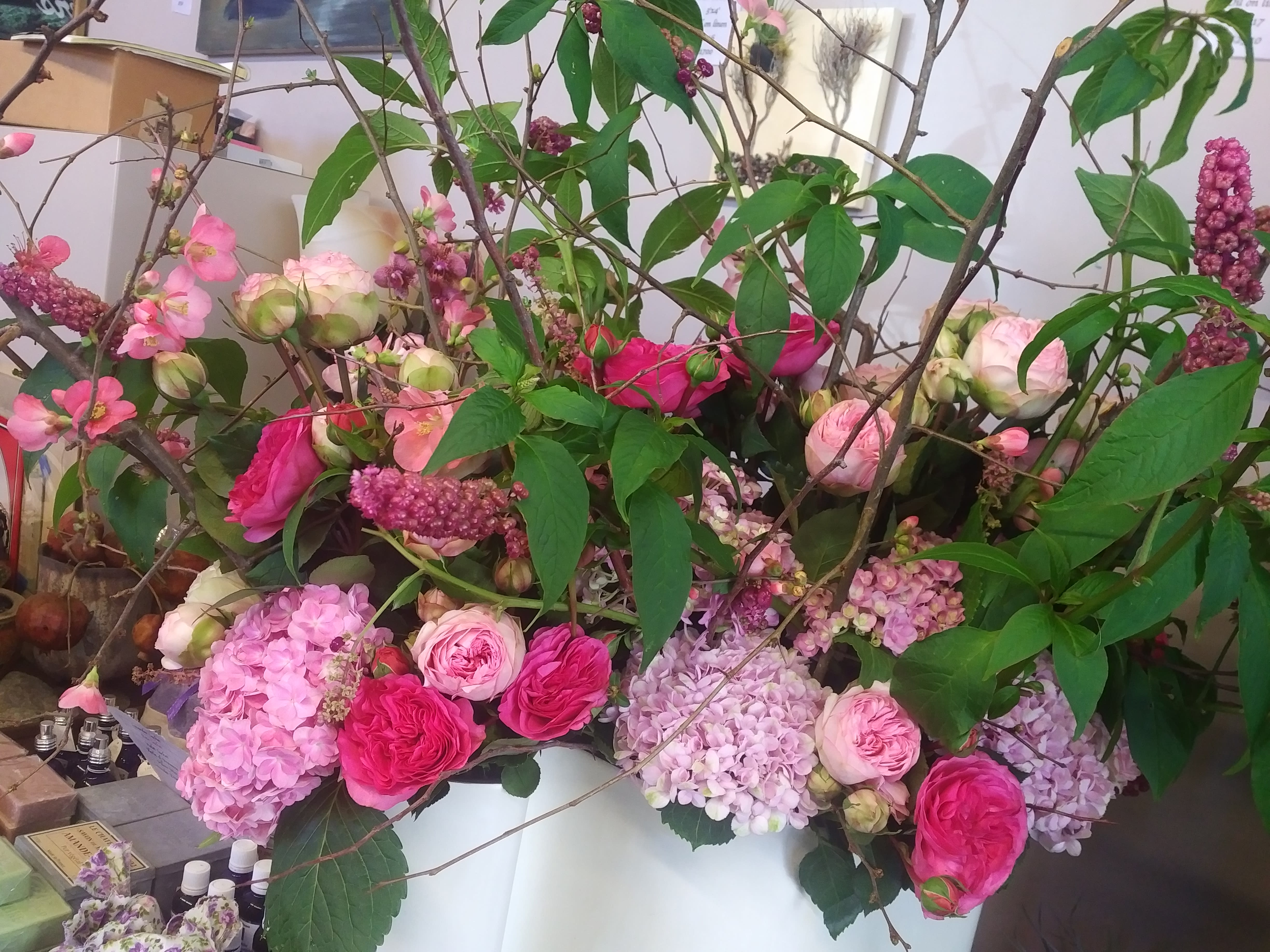 Large floral arrangement with pink roses and hydrangeas in a white container