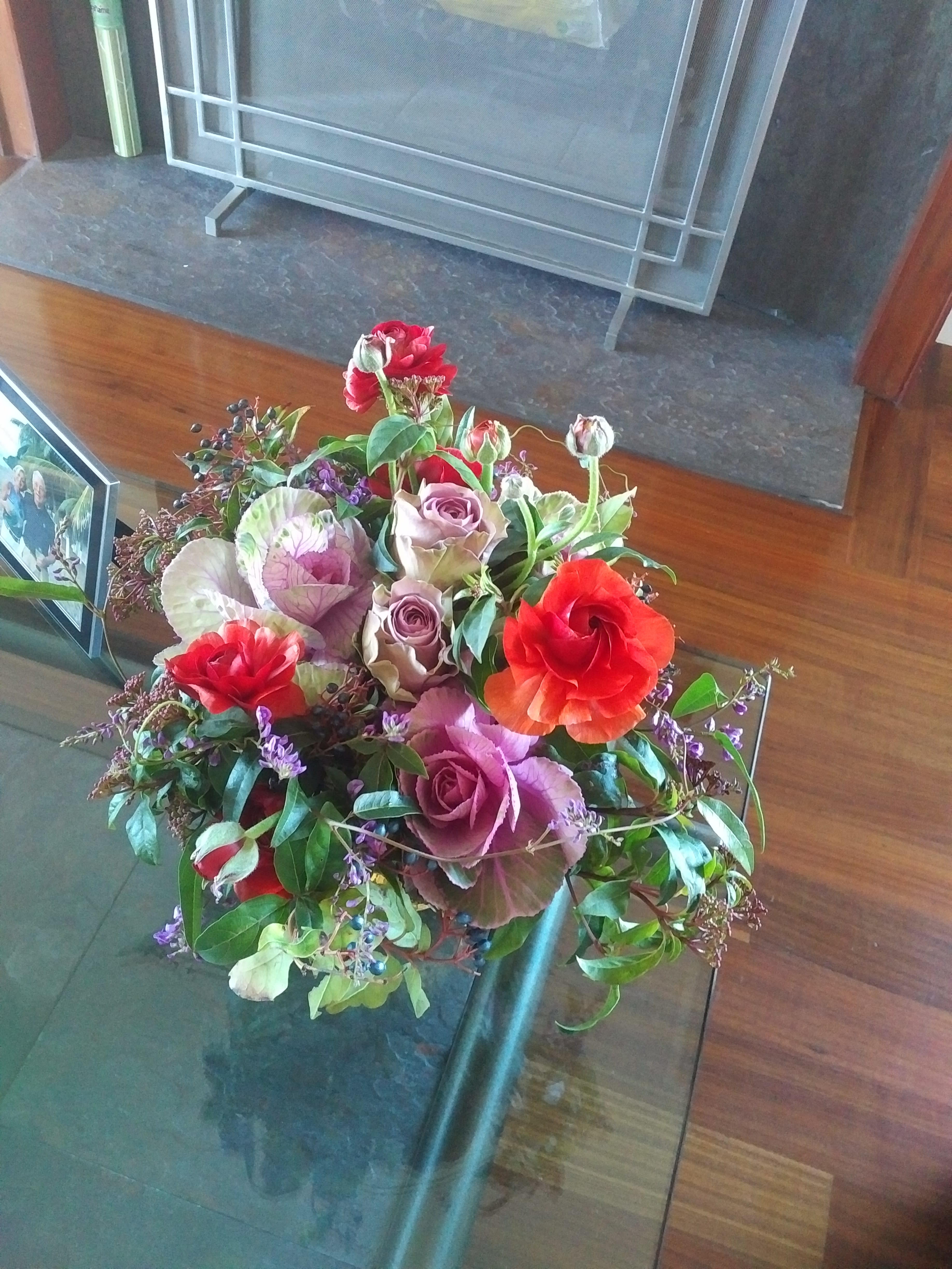 Mixed bouquet with red, pink, and purple flowers in a glass vase