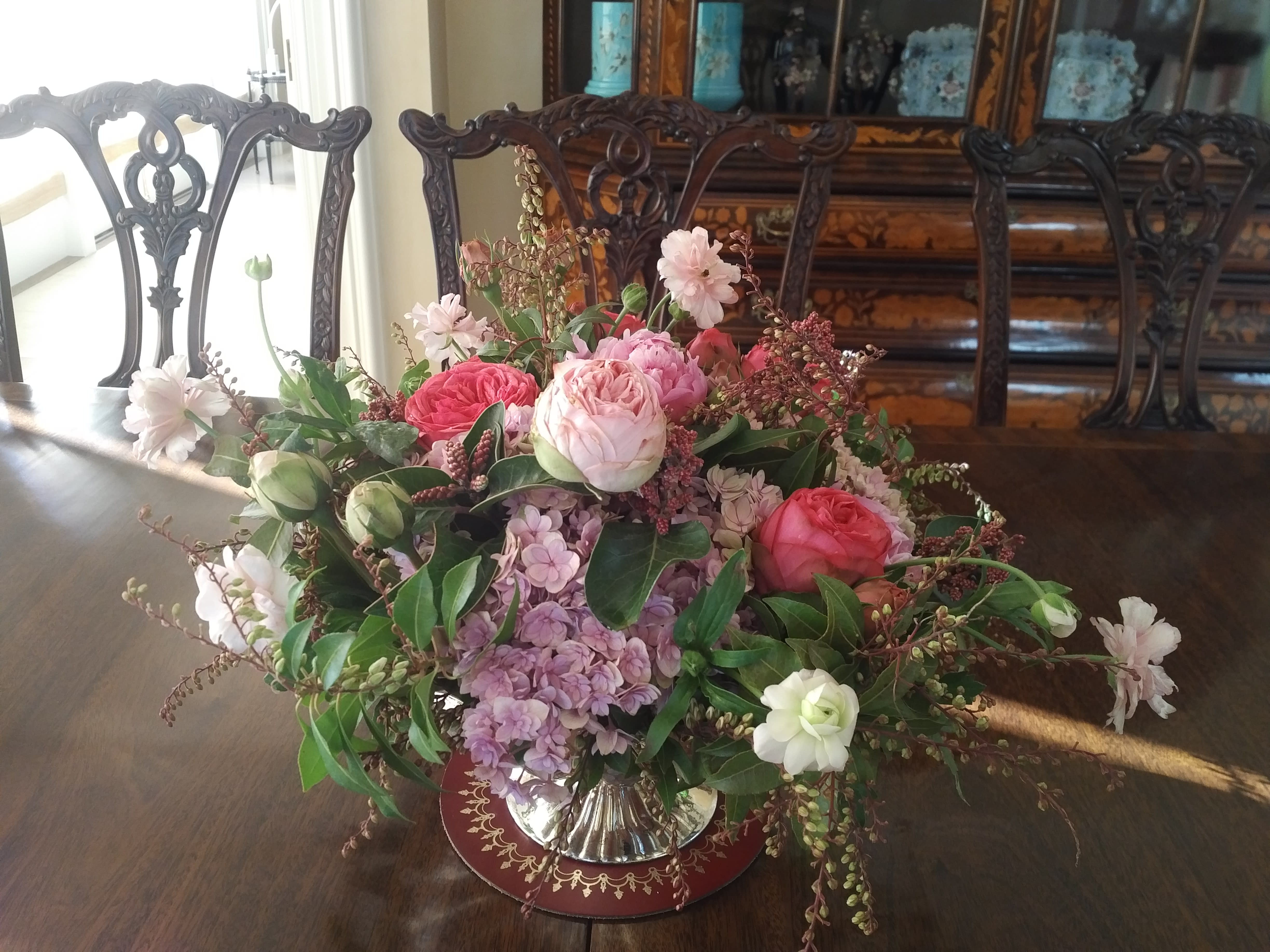 Pink and white rose arrangement in a silver vase on a table