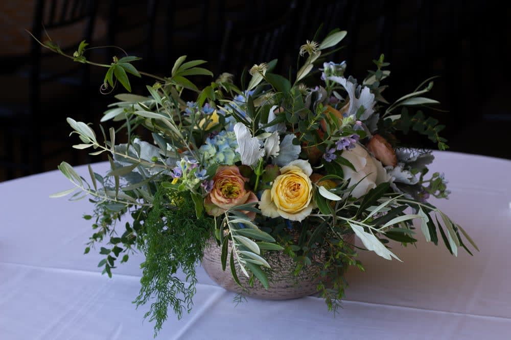 Low floral centerpiece with yellow and peach roses in a shallow bowl
