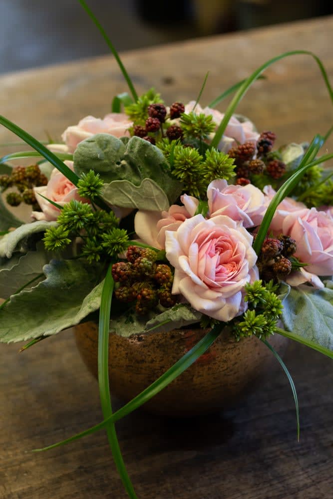 Pink roses arranged in a low bowl with green accents