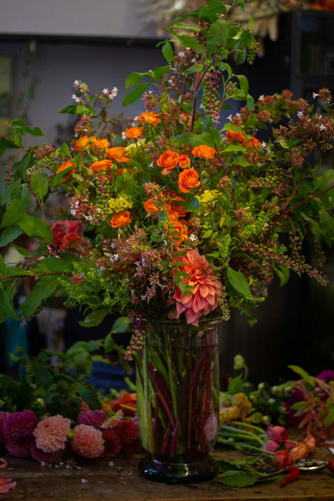 Tall mixed bouquet with orange roses and pink dahlias in a glass vase