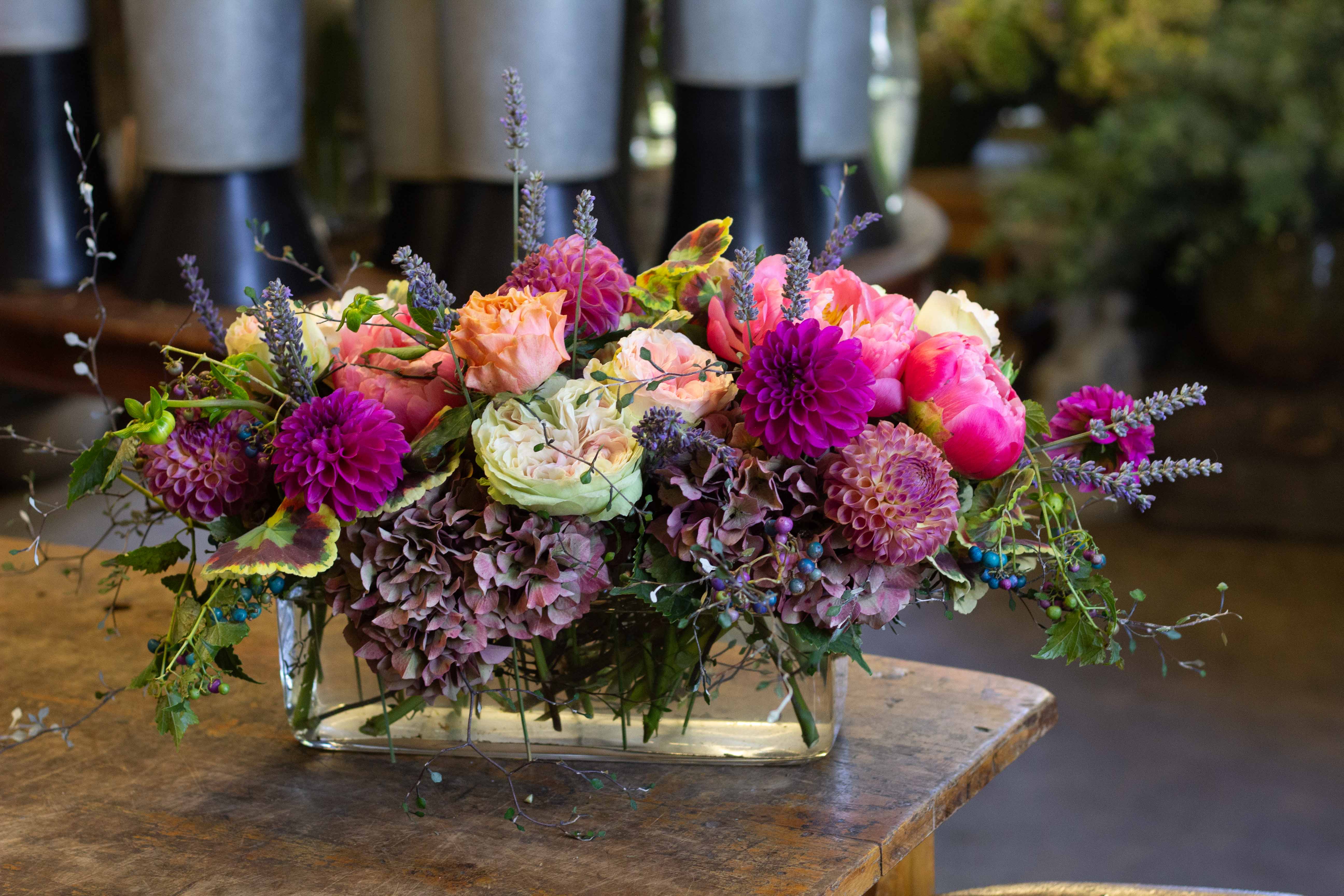 Low floral arrangement with pink, peach, and purple blooms in a glass vase