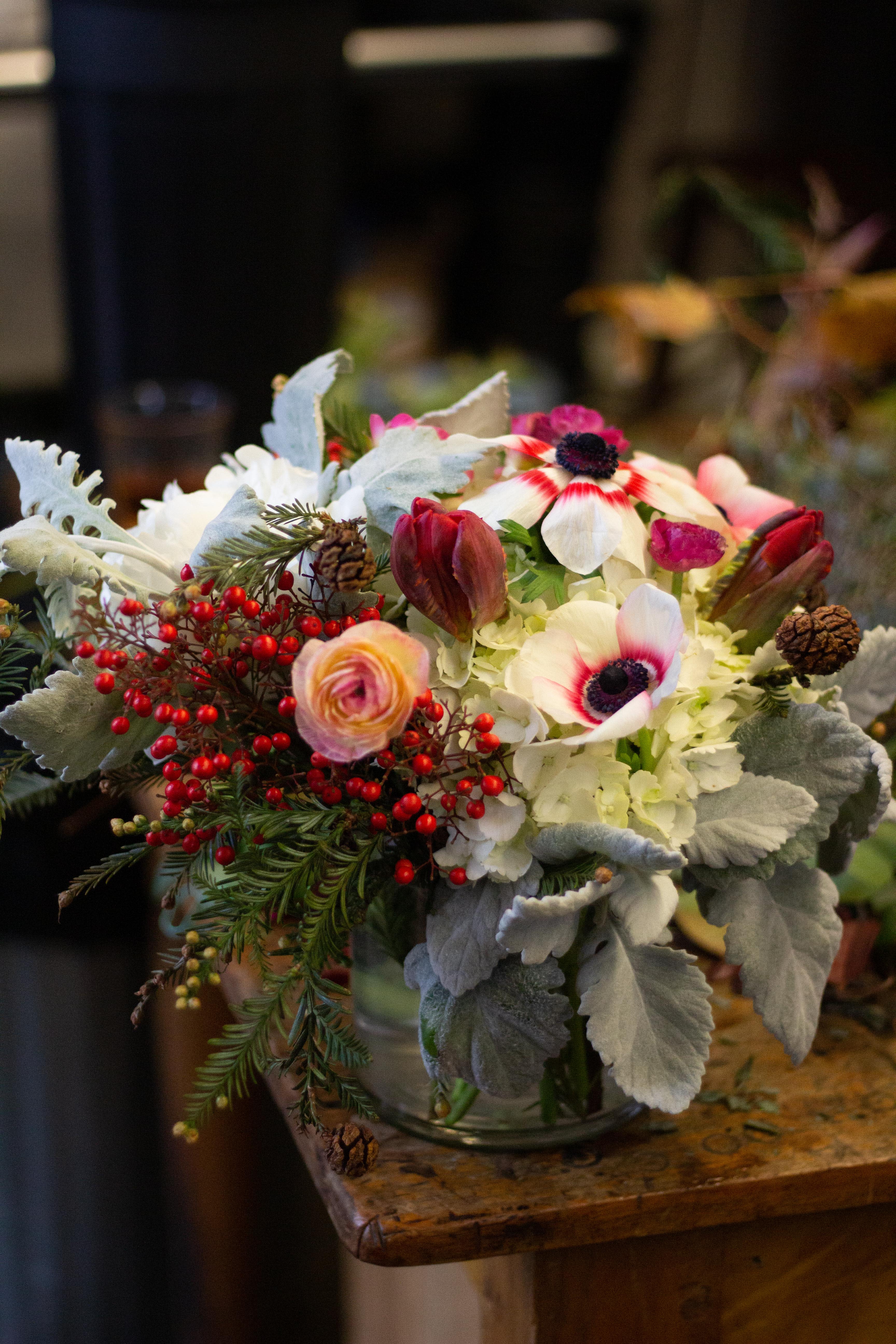 Bouquet of white and pink flowers with red berries in a glass vase