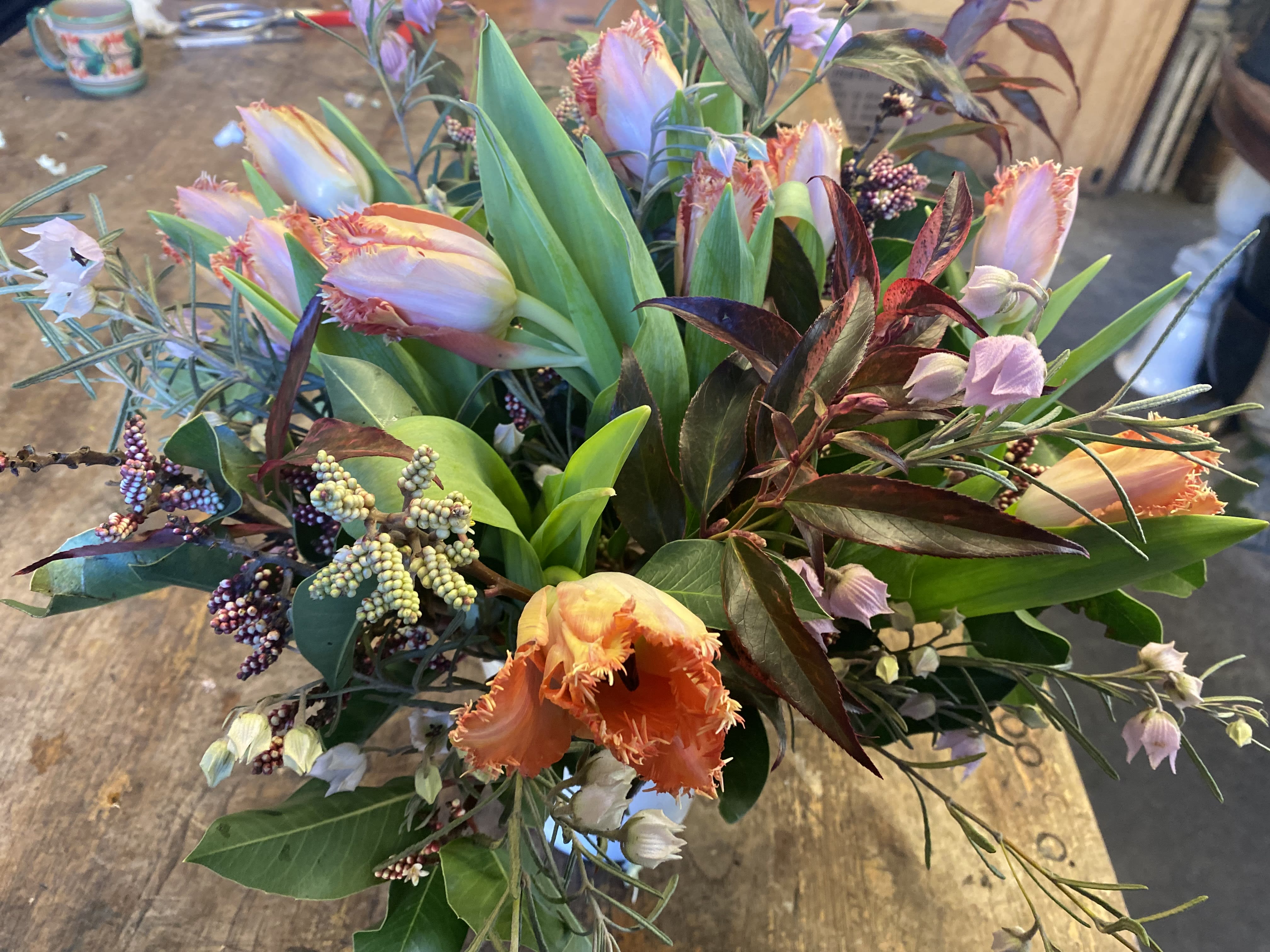 Bouquet of fringed tulips and mixed foliage on a table