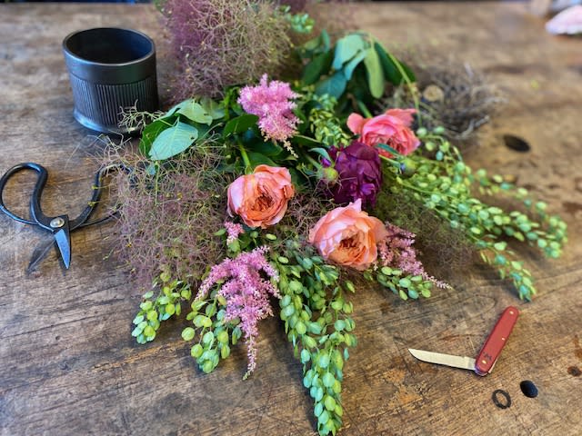 Loose floral arrangement with pink roses and purple blooms on a wooden table