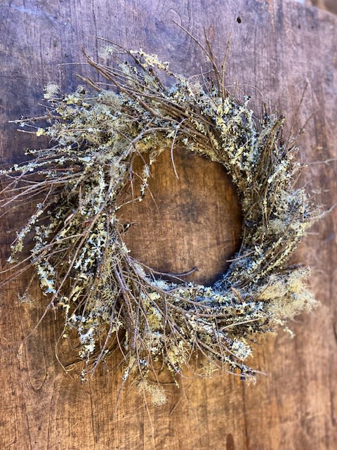 Rustic twig wreath with pale lichen on a wooden background