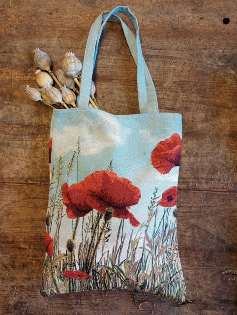 Tote bag with red poppy print and dried seed pods tucked in the handle