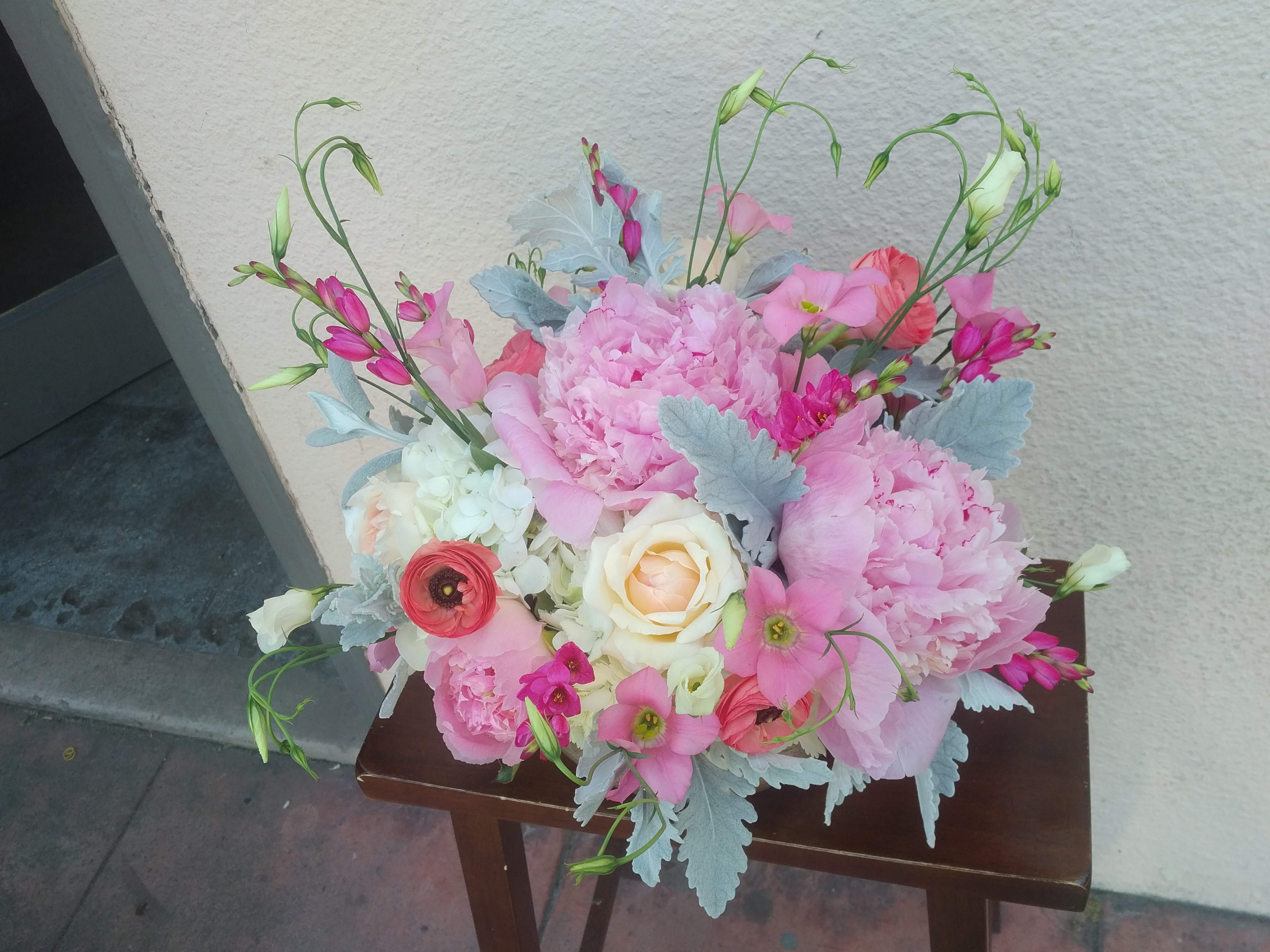 Pink floral arrangement with roses and peonies on a small table
