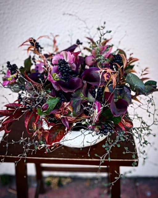 Purple floral arrangement in a white bowl vase