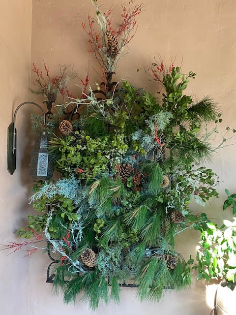 Large wall arrangement of pine, berries, and pinecones with a lantern