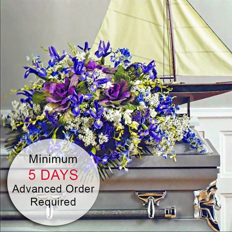 Purple and blue casket spray with white accents displayed on a gray casket