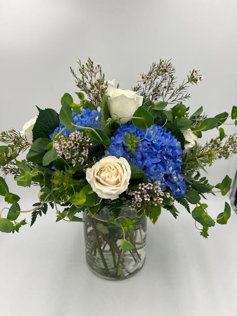 Blue hydrangeas and white roses in a glass vase