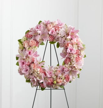 Loving Remembrance -  The Loving Remembrance Wreath is a blushing display of grace and beauty to honor the life of the deceased at their final tribute. Pink roses, Oriental lilies, gladiolus, hydrangea and carnations are brought together with lush greens to form the shape of a wreath, offering warmth and comfort with its sweetly sophisticated elegance. Displayed on a wire easel. 
