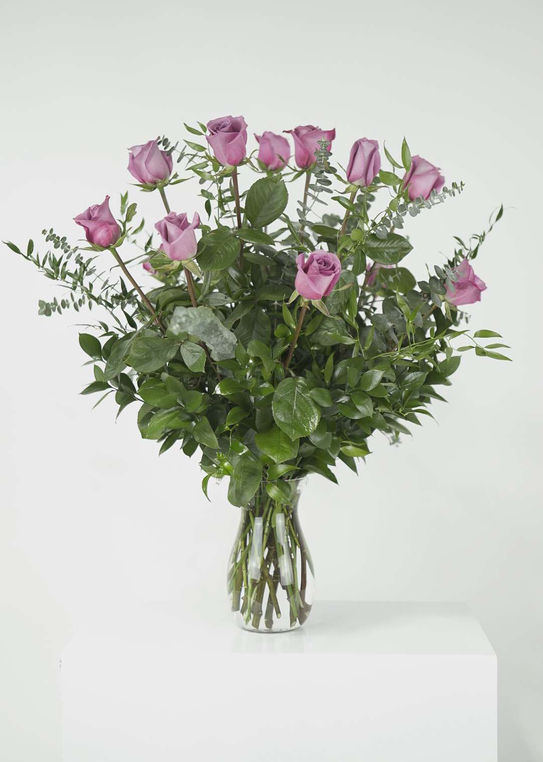 Pink roses in a clear glass vase with mixed greenery