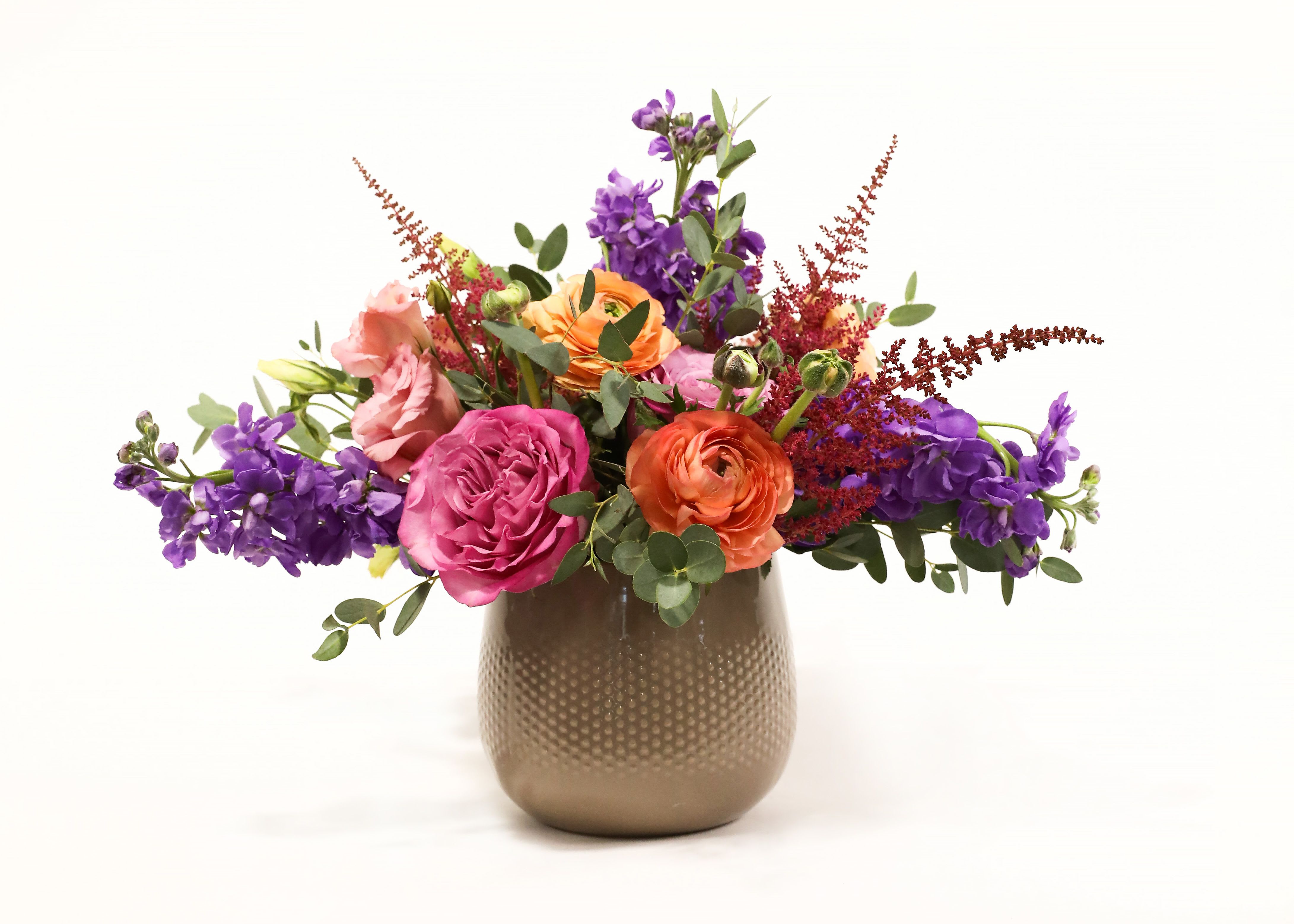 Colorful bouquet of roses and purple flowers in a gold vase