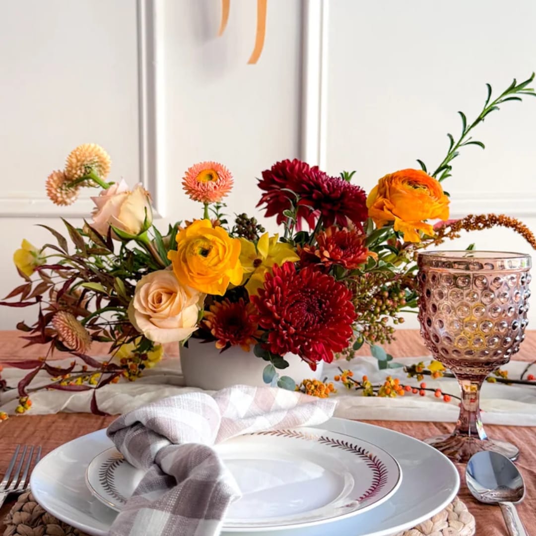 Mixed floral centerpiece in a low white vase with roses and chrysanthemums