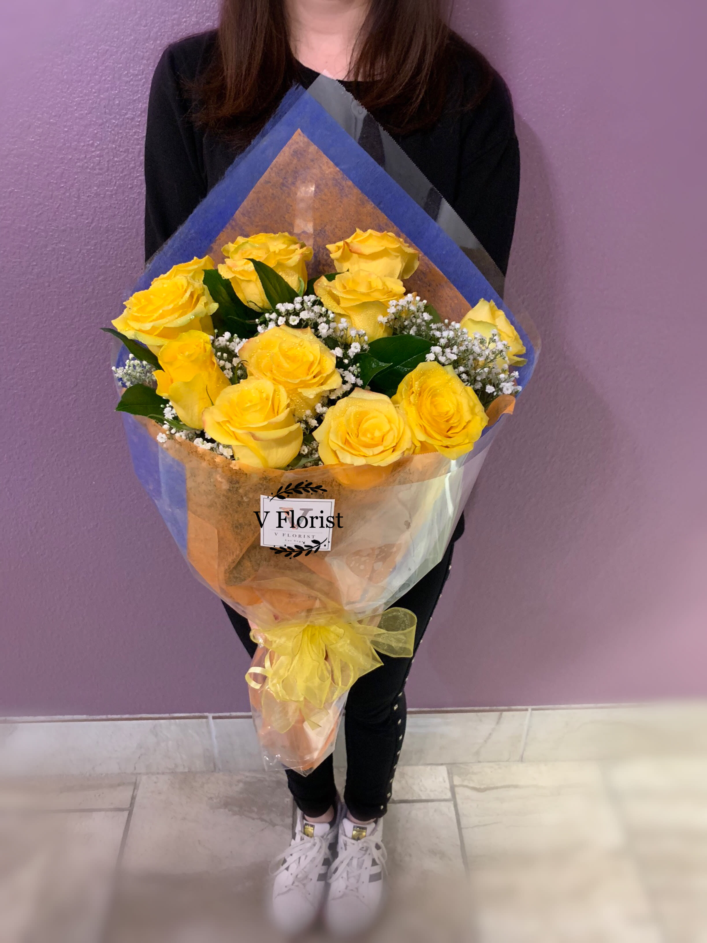 Bouquet of yellow roses wrapped in blue and clear paper