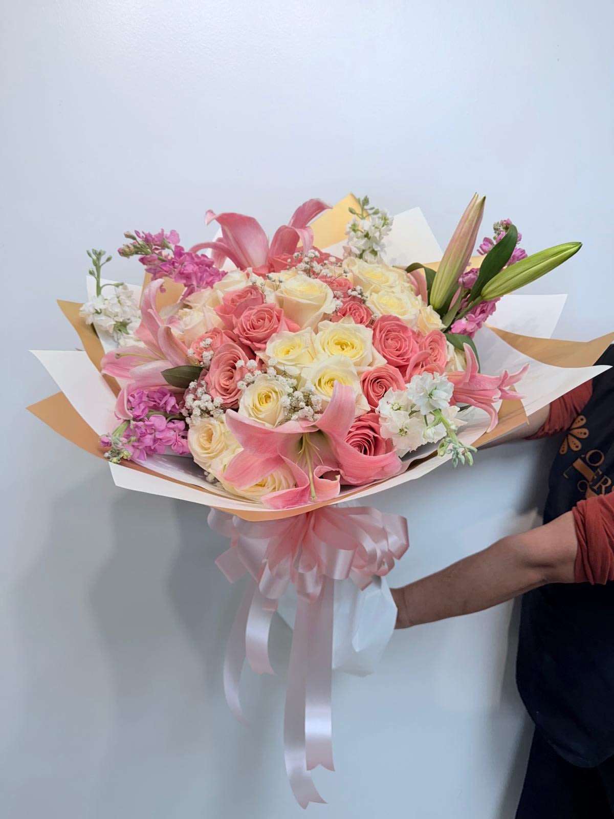 Pink and cream bouquet of roses and lilies wrapped with a ribbon
