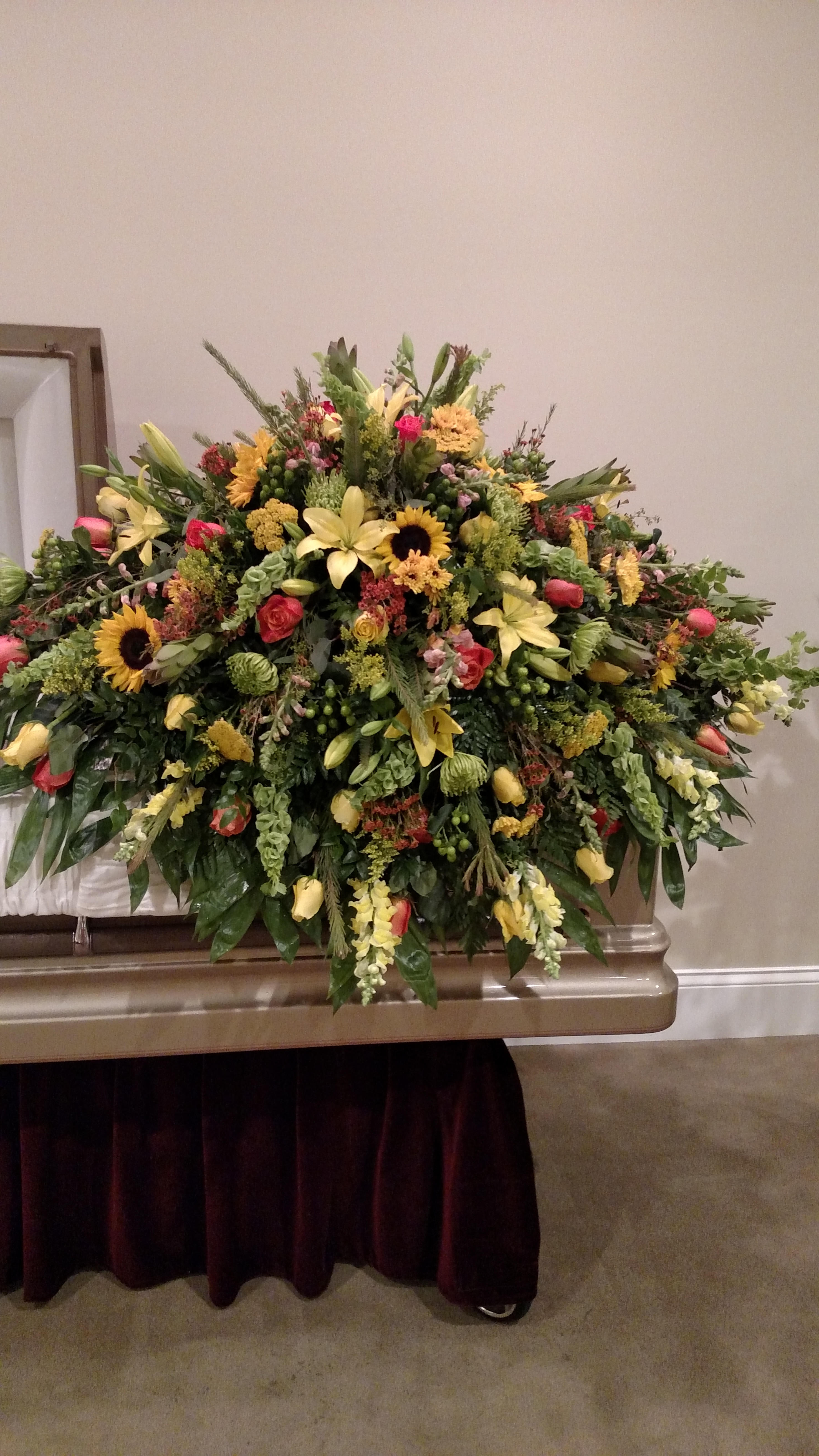 Large mixed floral spray with yellow lilies, sunflowers, and roses