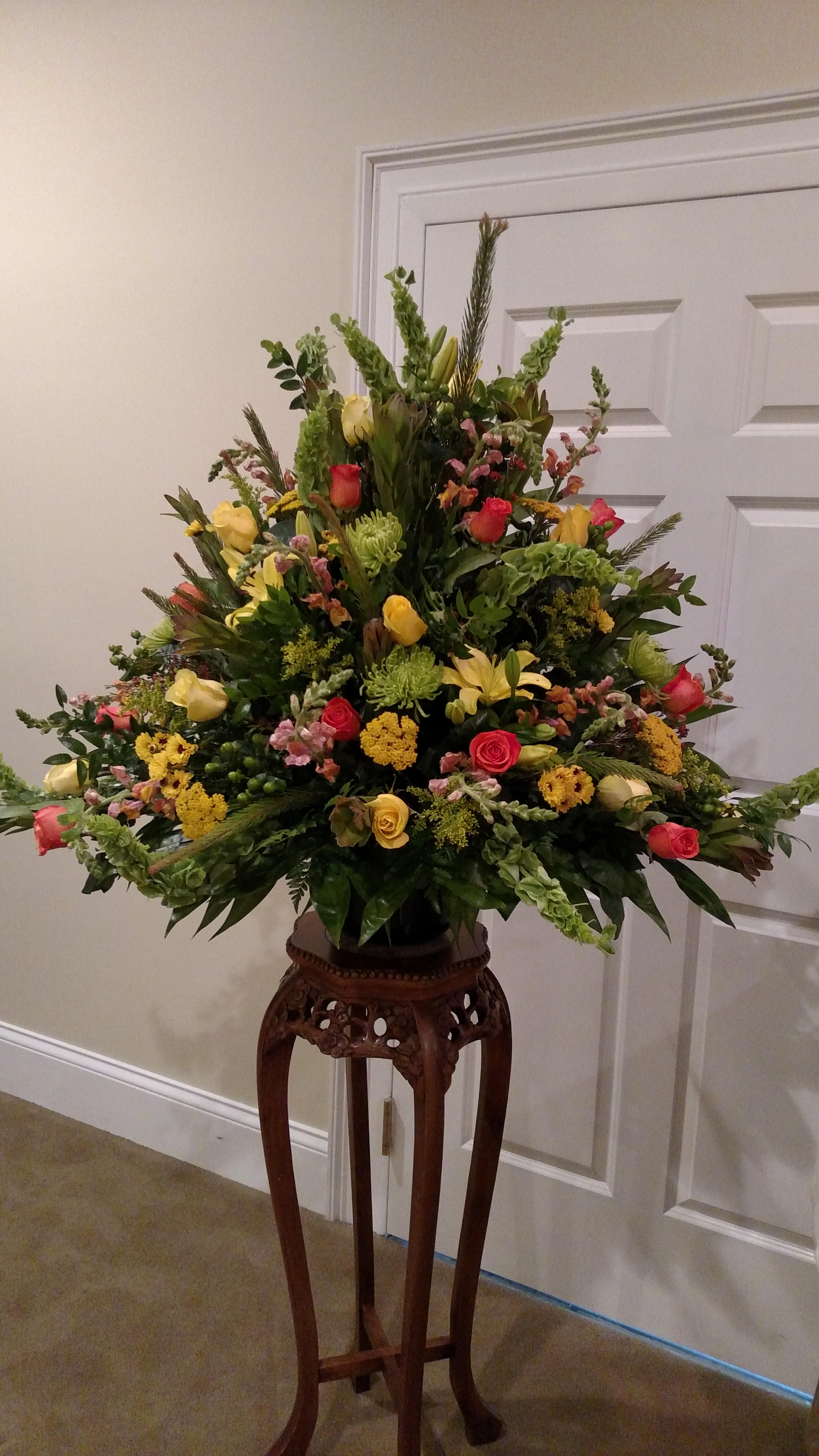 Large mixed flower arrangement on a carved wooden stand