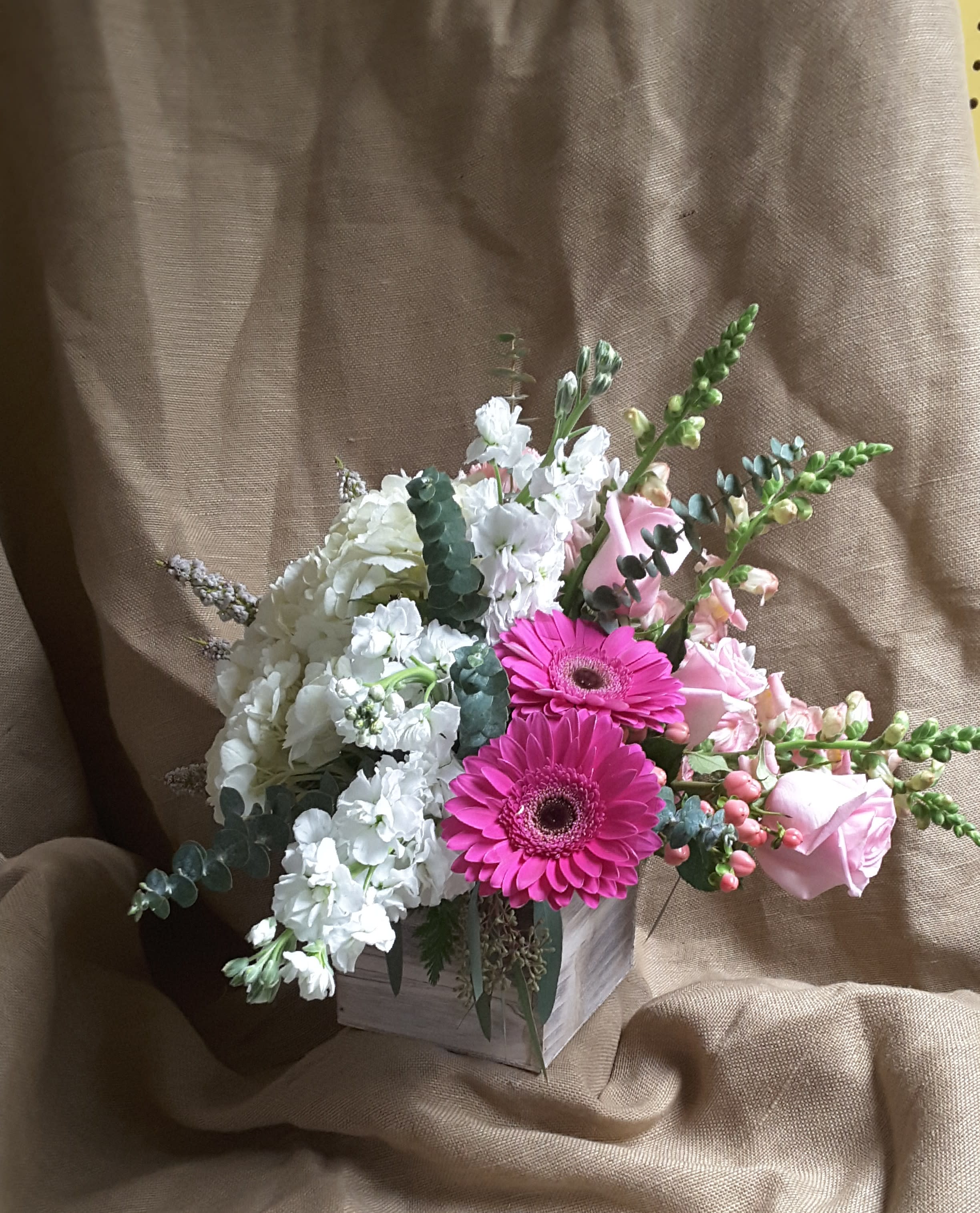 Pink gerbera daisies and white flowers in a small wooden box