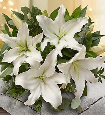 White lily bouquet with green foliage on a gray cloth