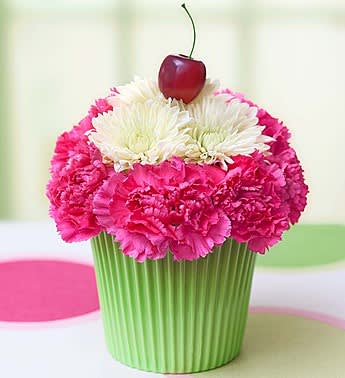 Cupcake-shaped flower arrangement with pink and white blooms topped by a cherry