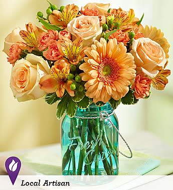 Peach roses and orange daisies in a turquoise glass jar