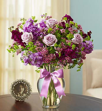 Lavender and purple bouquet in a clear vase with a pink ribbon